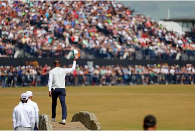 Tiger Woods doffs his cap to the crowd as he crosses the Swilken Bridge during his walk down the 18th hole at the end of his second round at the 150th Open Championship.